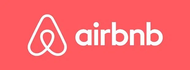 Airbnb logo with a white abstract symbol and the word "airbnb" in lowercase white letters on a coral pink background.