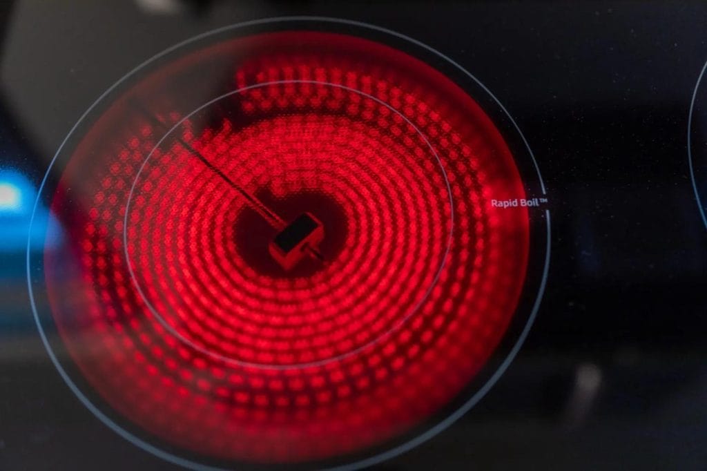 A close-up of an electric stovetop burner glowing bright red, indicating it is turned on and hot, with the words "Rapid Boil" visible near the edge of the circular heating element.